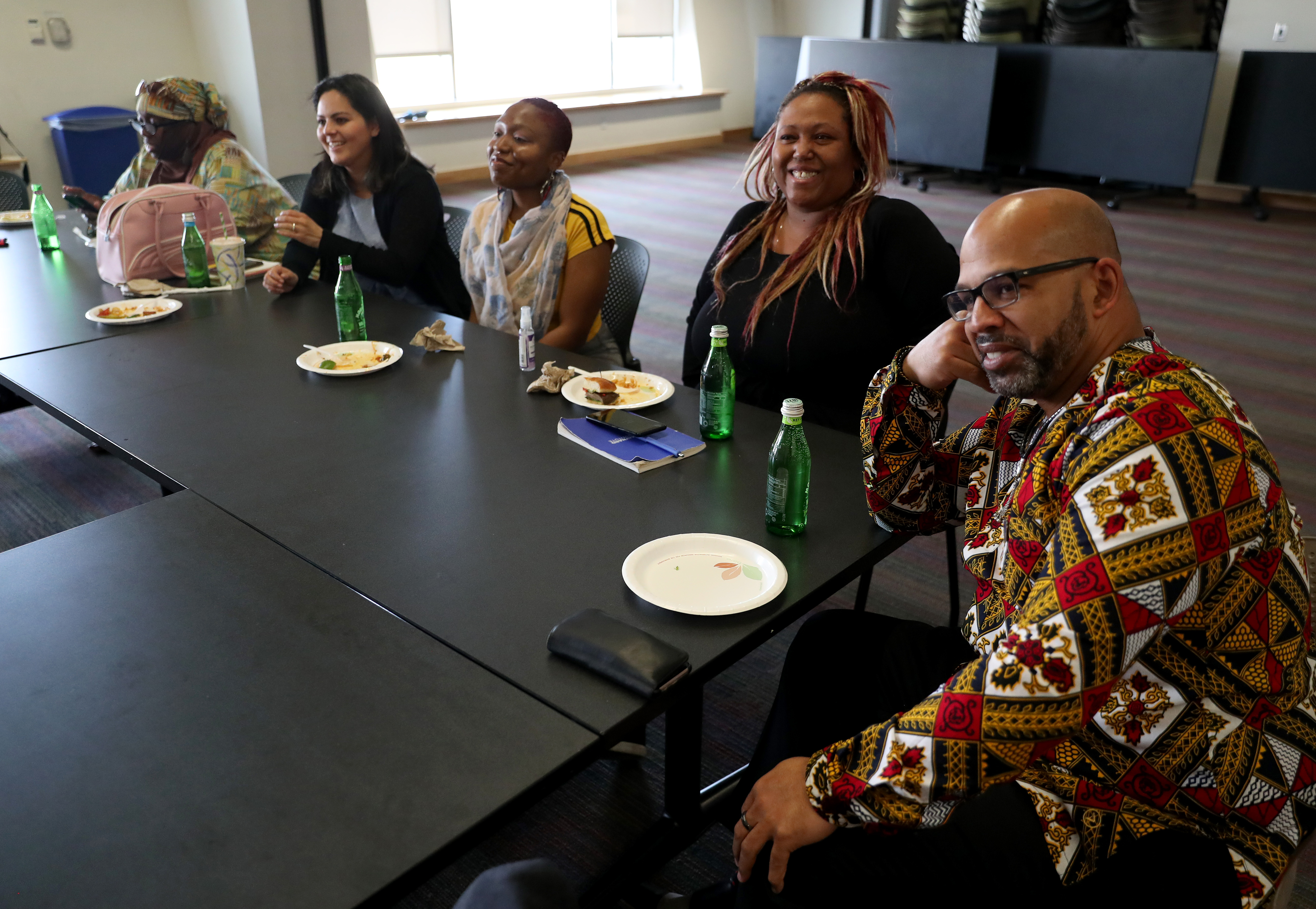 A group of community journalists sit at a table to listen to speakers.