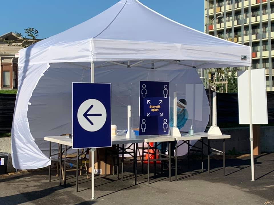 A white tent with a table inside for COVID testing.