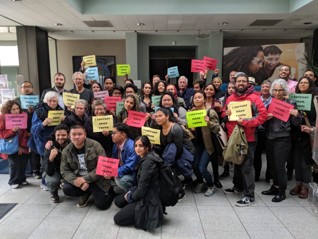 A large group holds signs that say support AROC