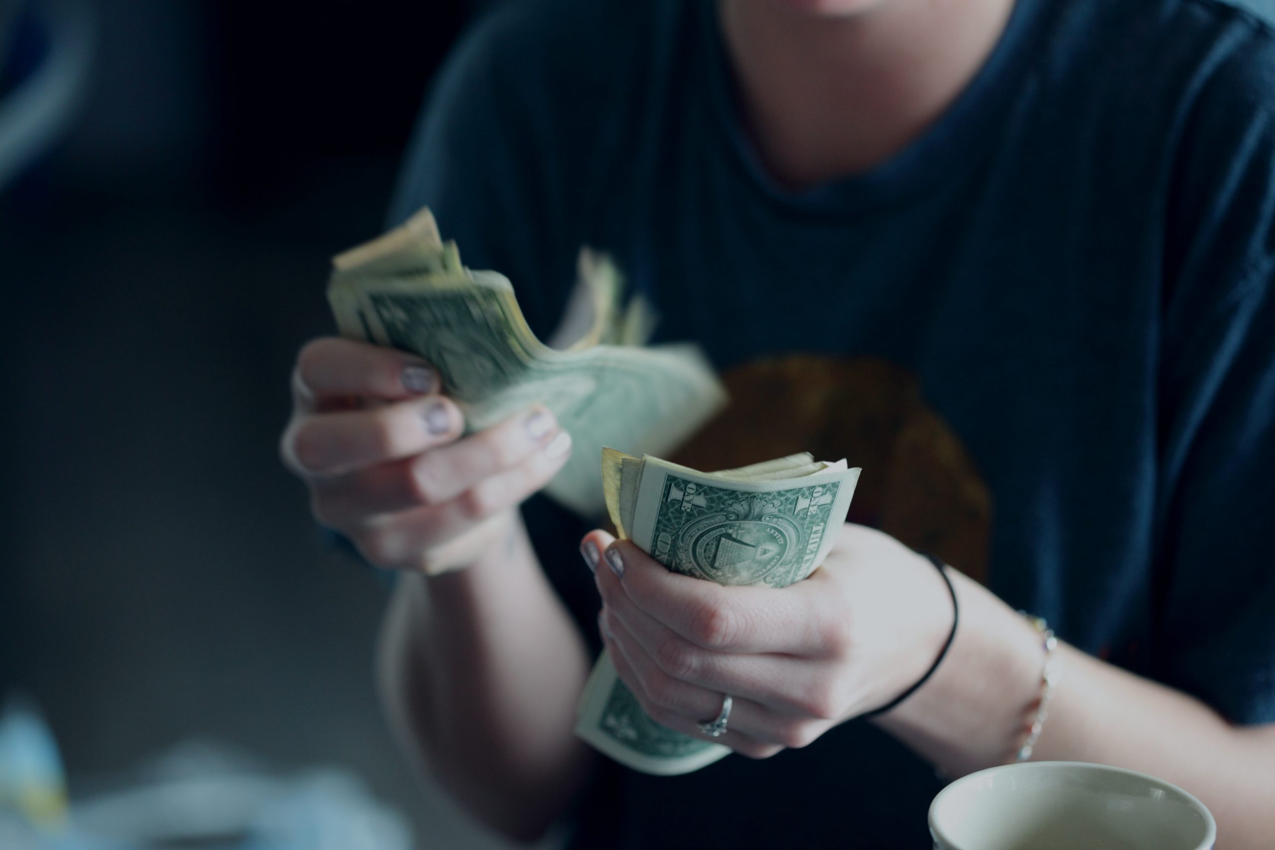 A close up of a person counting dollar bills.