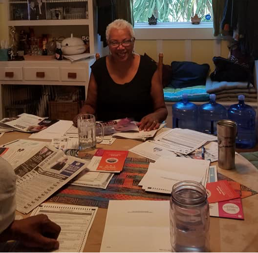 An African American woman with short grey hair sits at a table.