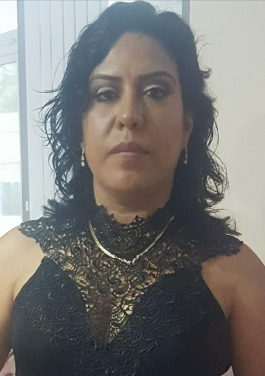 A photo of a Latina woman wearing a decorative black and gold top takes a selfie