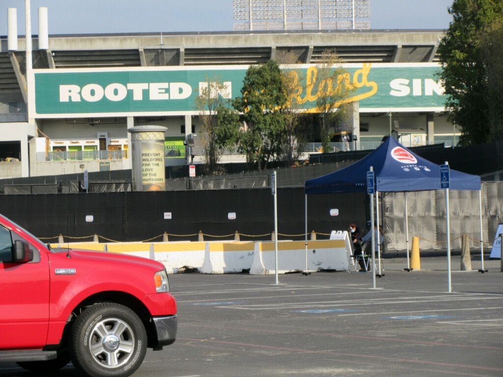 An image of the parking lot in the Oakland Coliseum with the baseball stadium in the background.