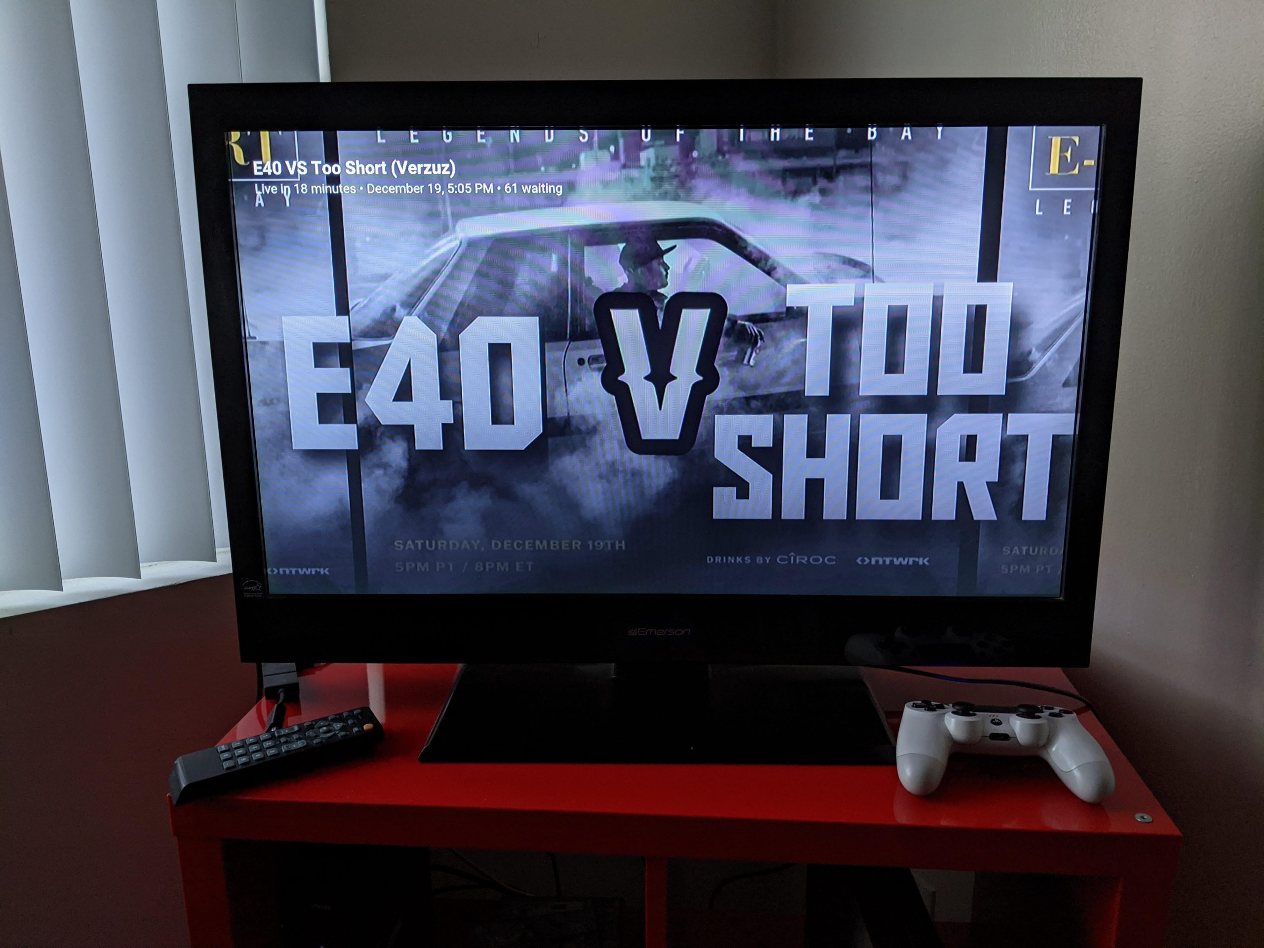 An image of a large TV with "E-40 V Too Short" on the screen