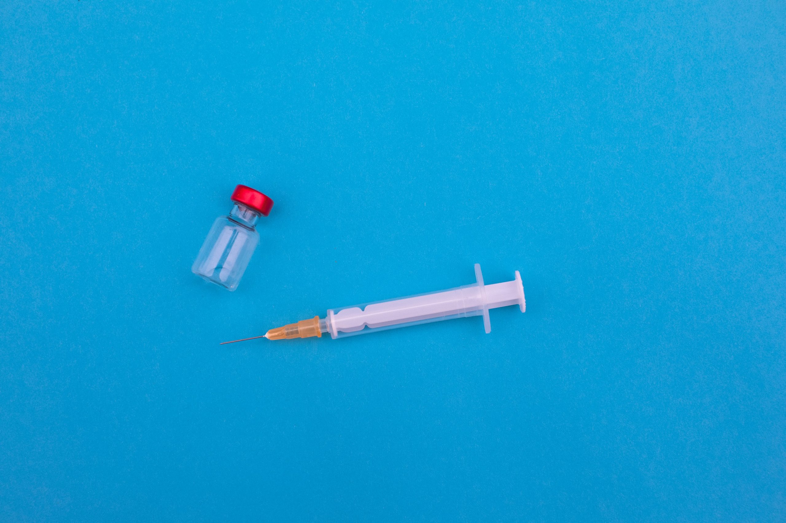 image of a vial and needle against a blue background