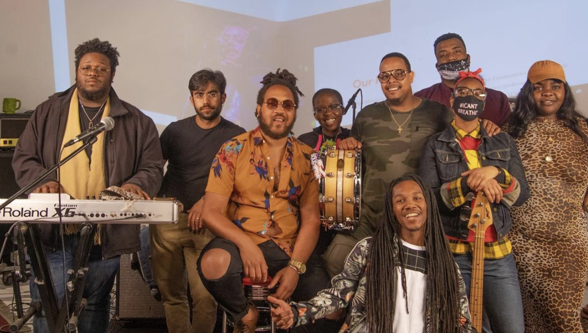 A group of Black and African American people standing near keyboard and other instruments in a band.