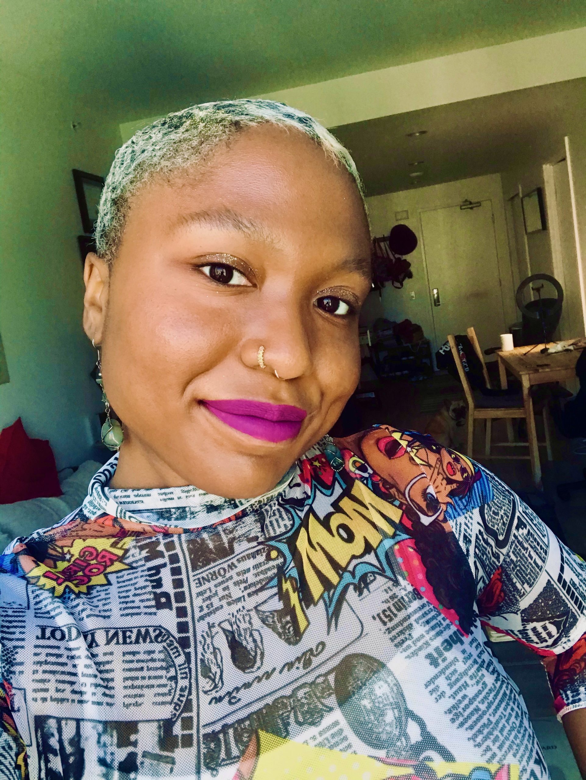 A Guyanese American woman with short blond hair and a brightly colored shirt smiles at camera