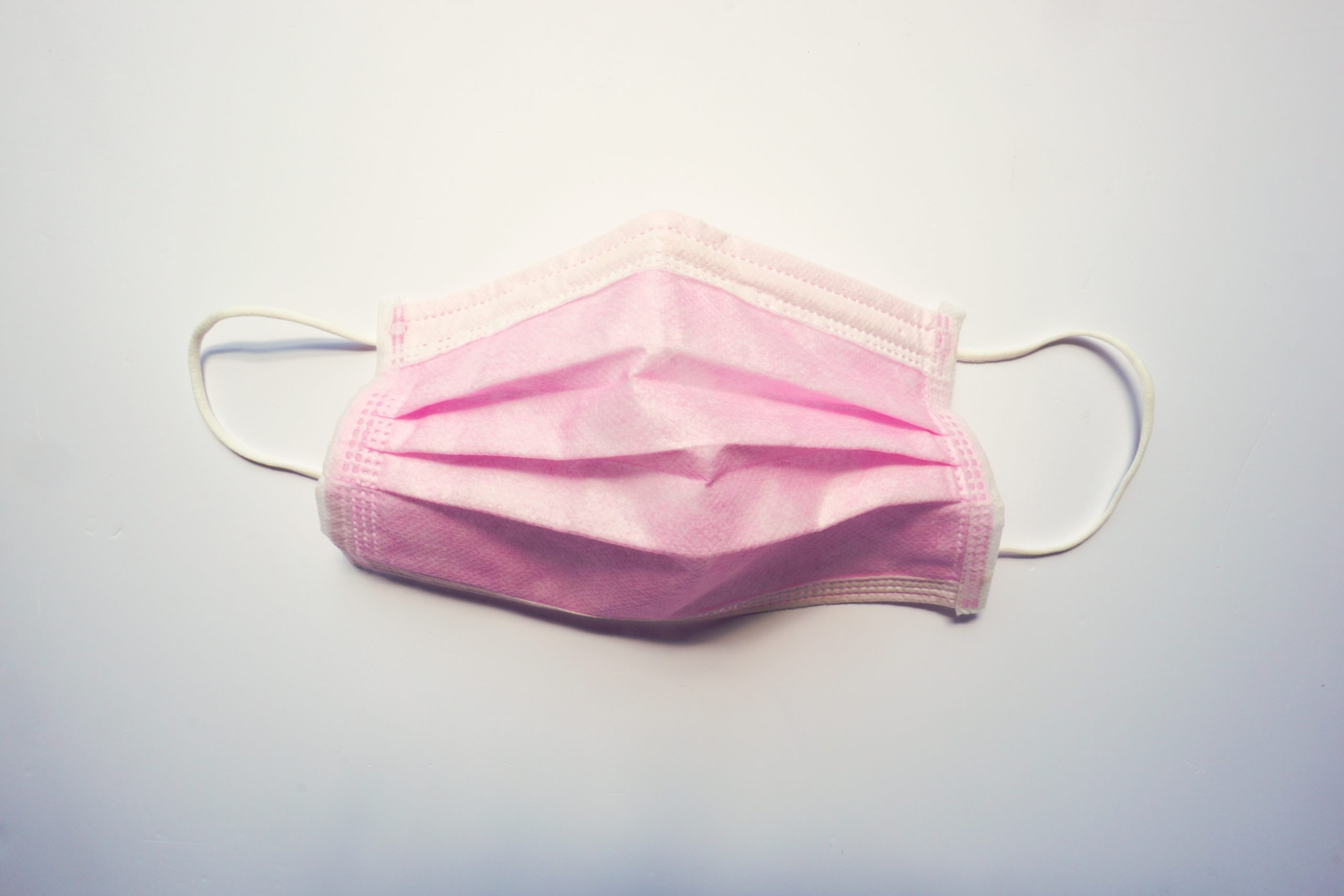 a pink surgical mask lays on a white background