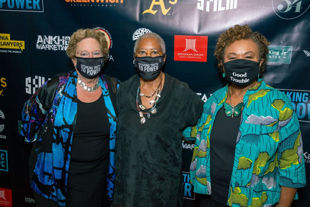 three women post for a photo in front of a backdrop at the Grand Lake Theatre.