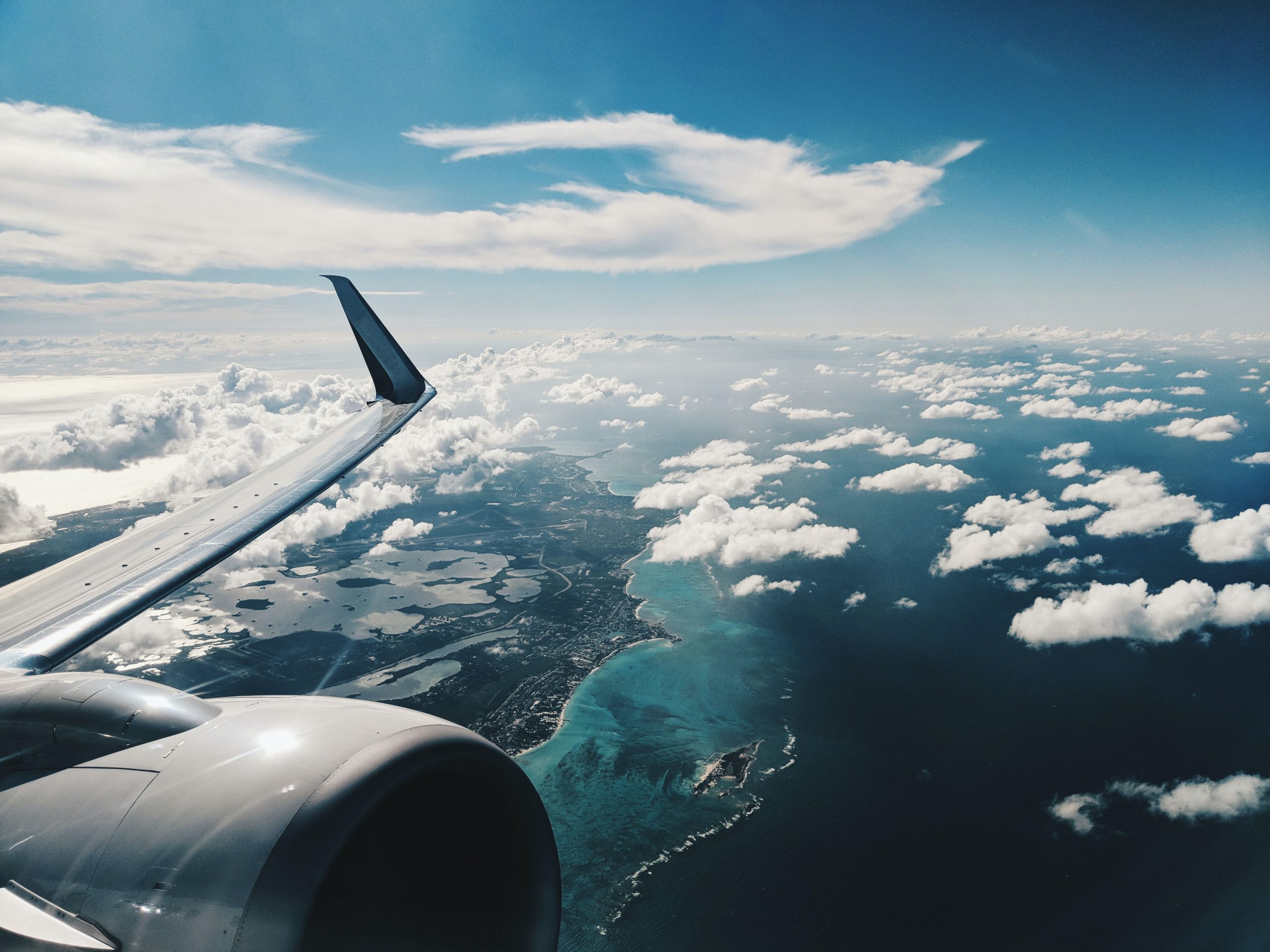 Airplane wing against a blue cloudy sky