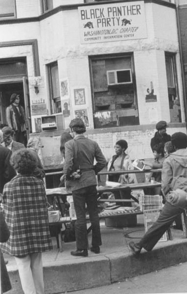 A black and white image of Black men and women in front of a health clinic