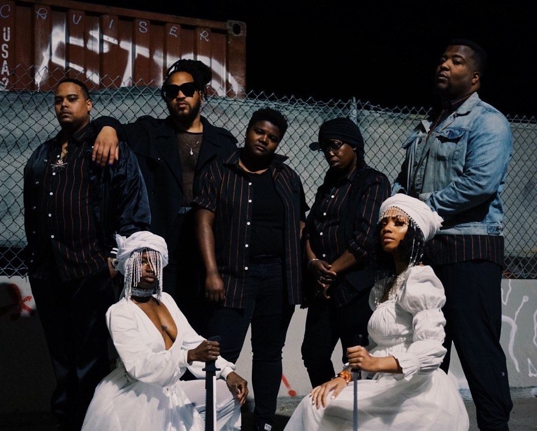 A group of African American band members, including two women wearing white dresses.