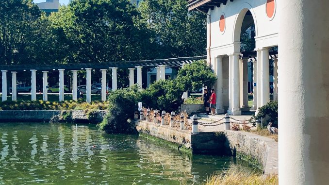 image of columns next to greenish lake and some trees