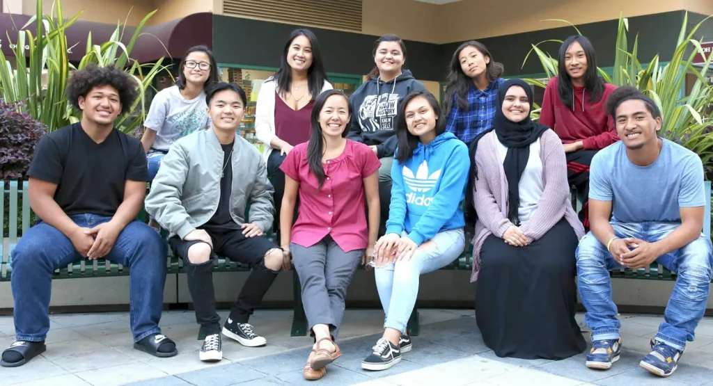 a large group of Asian Pacific Islander and Arab American students sit outside for a nice group photo