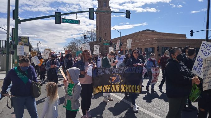 Image of a crowd holding signs walking down the street.