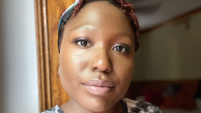 An African American woman with short hair and wearing a scarf tied around her head in a selfie