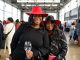 Two African American women wearing nice hats hold a wine glass and smile at an indoor spacious Black wine festival in Oakland