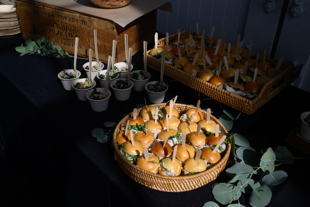 A spotlighted image of a large tray of round sliders at a catered event