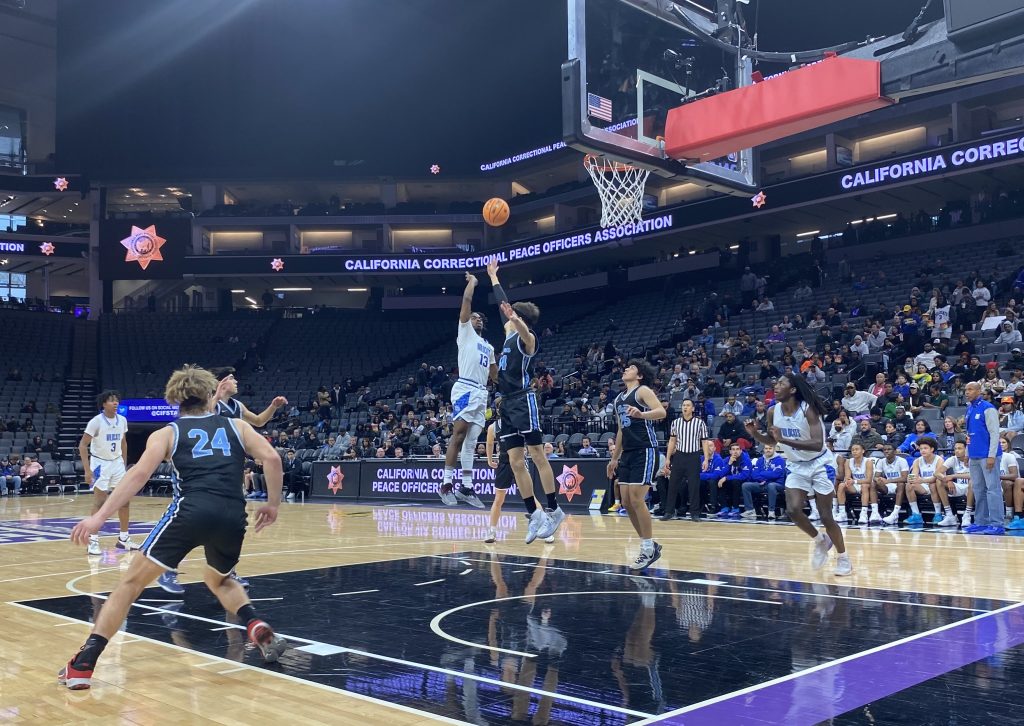 A young man throws a basketball in the net during a high school game