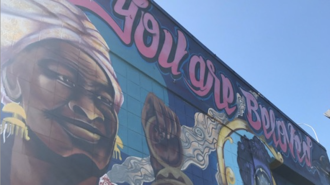 A colorful mural with "You are beloved" and Harriet Tubman and others