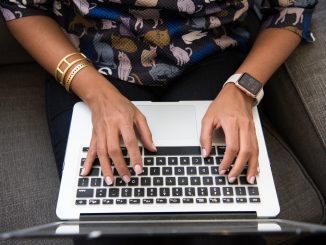 an overhead view of a woman's hands typing on a laptop