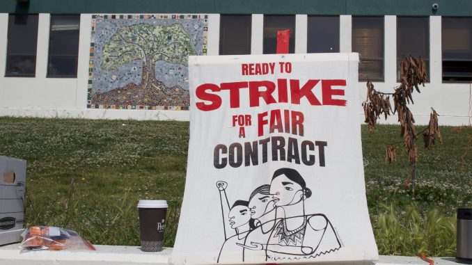 A canvas sign on a stick that says "strike for a fair contract"