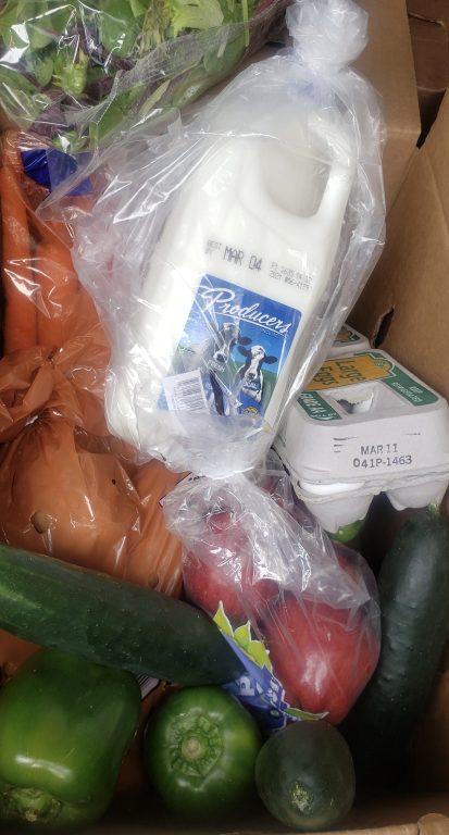 close image of a box of groceries, eggs and milk