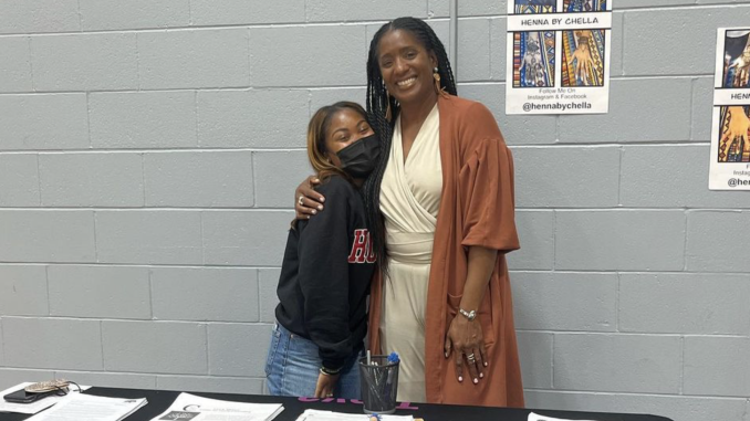 A young Black girl hugs a Black woman at an event