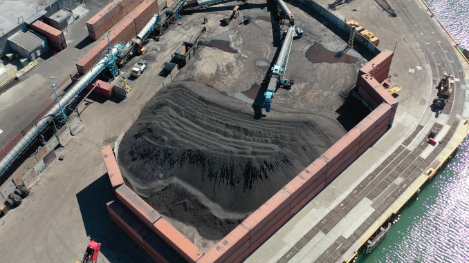 A drone aerial shot of large pile of dark dust, which is coal, inside an open top container