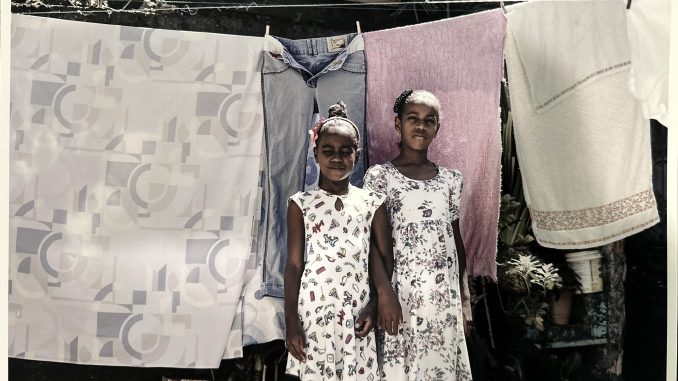 Two girls in El Salvador stand in front of a clothing line