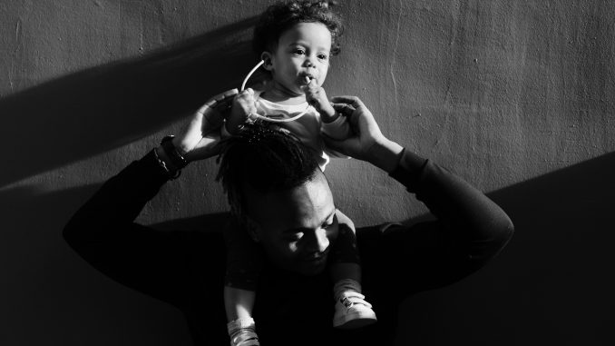 a black and white photo of a Black father holding up his child