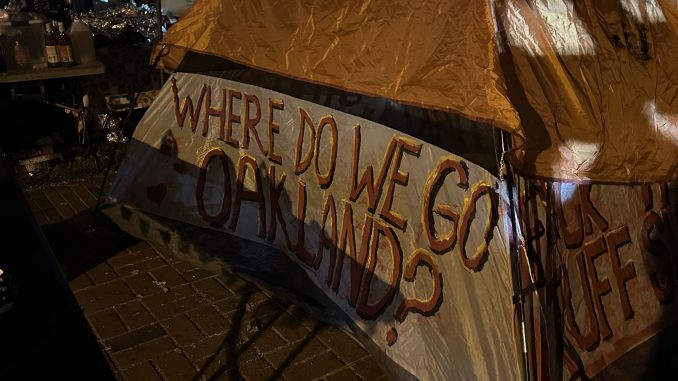 Orange and white tent with letters asking, "Where do we go, Oakland?"