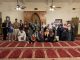 a group of people in a mosque holding copies of a book