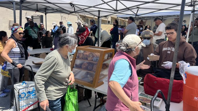 Groups of people gathering to receive food at the Sliding Scale Cafe.