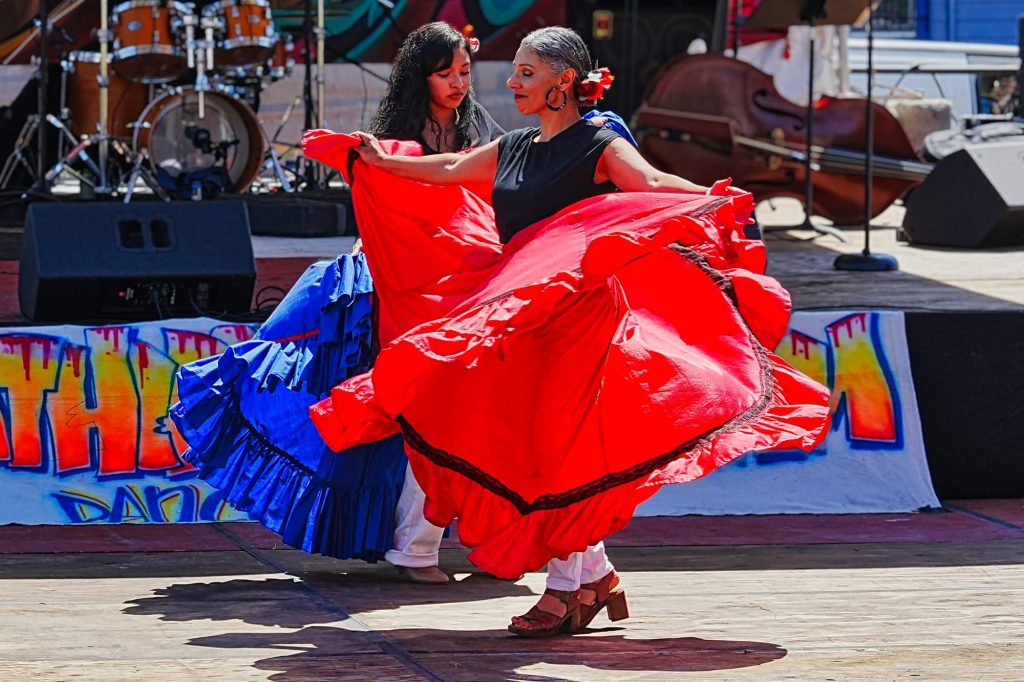 Two Cultura y Tradición dancers perform in red and blue dresses during the Malcolm X JazzArts Festival in Oakland on May 16, 2026.