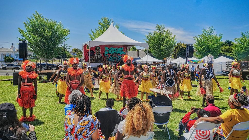 Men and women in colorful West African-inspired clothing dance during the Malcolm X JazzArts Festival in Oakland.